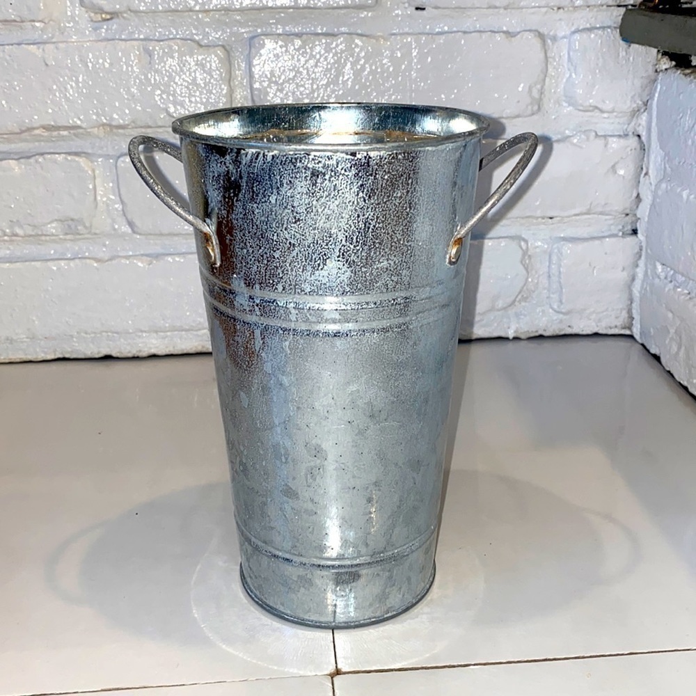 Weathered silver tone metal vase with handles. Plastic liner. 9” by 5”.